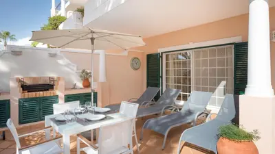 a patio with a table and chairs and an umbrella at Joanne in Vale do Lobo