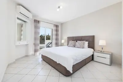 a white bedroom with a large bed and a window at Apartament Portes Balaia Golf Resort in Albufeira