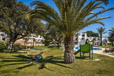 a palm tree in a park with a playground at Apartament Portes Balaia Golf Resort in Albufeira