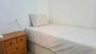 a small bedroom with a bed and a wooden dresser at Cozy Garden T1 near the beach in Albufeira