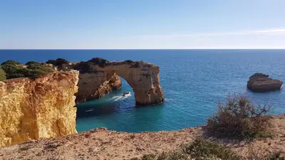 an arch in the ocean with a person in the water at Cozy Garden T1 near the beach in Albufeira