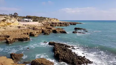 a group of rocks in the ocean with a beach at Cozy Garden T1 near the beach in Albufeira