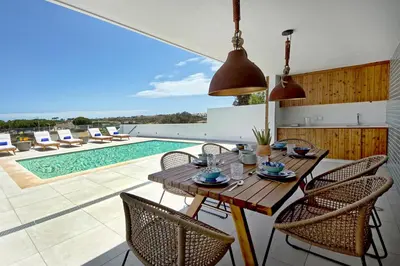 a dining room with a table and chairs and a pool at Villa Ocean Marina, Panoramic and heatable Pool by DreamvillasAlbufeira in Albufeira