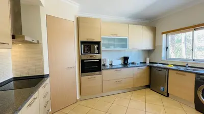 a large kitchen with wooden cabinets and appliances at Santa Maria N by Check-in Portugal in Albufeira