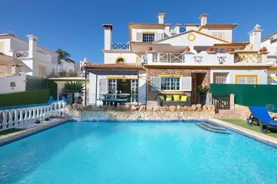 a house with a swimming pool in front of a house at Villa Calipso in Albufeira