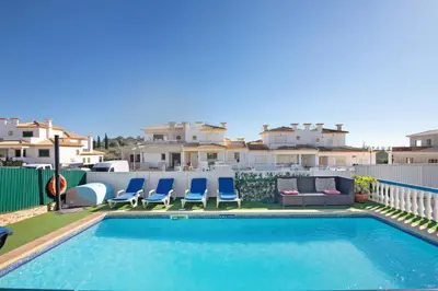 a swimming pool with chairs and a couch and some buildings at Villa Calipso in Albufeira