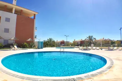 a large blue swimming pool in front of a building at Albufeira parque da CORCOVADA standing flat W/Pool in Albufeira