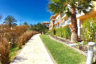 a walkway in front of a building with palm trees at Albufeira parque da CORCOVADA standing flat W/Pool in Albufeira