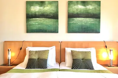 a bedroom with two beds and two paintings on the wall at Albufeira parque da CORCOVADA standing flat W/Pool in Albufeira