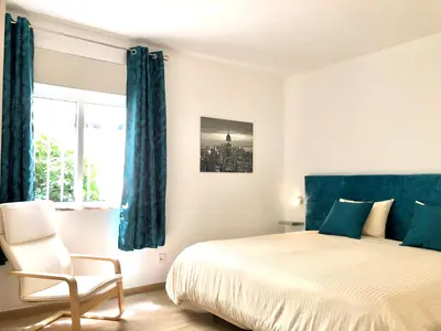 a bedroom with a bed and a chair and a window at Albufeira + appartement proche plage avec piscine in Albufeira