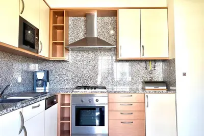 a kitchen with white cabinets and a stove top oven at Albufeira l AMAZING terrasse with jacuzzi Encosta da Orada in Albufeira