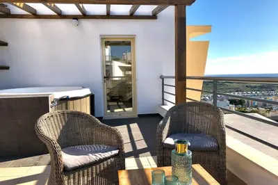 a patio with two chairs and a table on a balcony at Albufeira l AMAZING terrasse with jacuzzi Encosta da Orada in Albufeira
