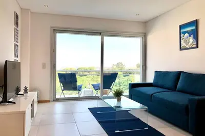 a living room with a blue couch and a large window at Falesia beach l roof top pool in Albufeira