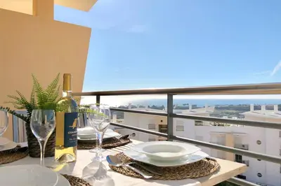 a table with plates and wine glasses on a balcony at Albufeira l encosta da Orada wonderful sea view in Albufeira
