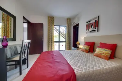 a bedroom with a large bed with red pillows and a desk at VILLA COELHO in Albufeira