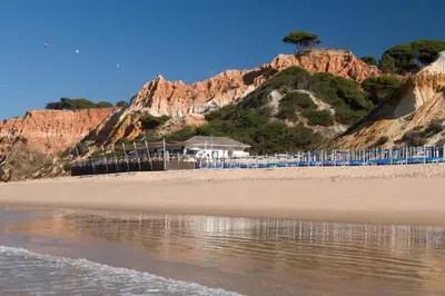 people standing on a beach next to the water at Pool and Garden Village-near beach in Albufeira