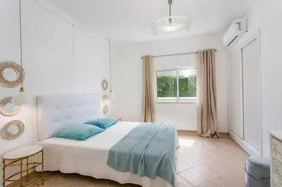 a white bedroom with a bed and a window at Villas Mar e Brisa in Albufeira
