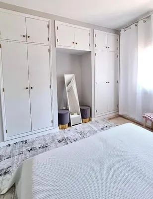 a white bedroom with white cabinets and a bed at Feliz Algarve in Albufeira