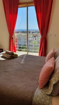 a bedroom with a bed with red curtains and a window at Sunny Apartment with sea view in Albufeira in Albufeira