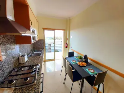 a kitchen with a table with chairs and a stove at Sunny Apartment with sea view in Albufeira in Albufeira