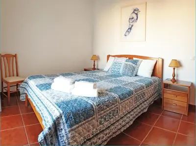 a bedroom with a bed with a blue and white blanket at Apartamento Carvalhal in Quarteira