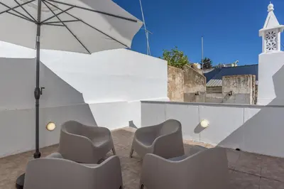 a patio with chairs and an umbrella and a church at FLH Faro Central House with Terrace in Faro
