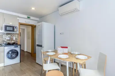 a kitchen with a table with chairs and a refrigerator at FLH Faro Central House with Terrace in Faro