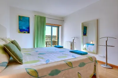 a bedroom with a large bed and a large window at Marina Sand Residence in Albufeira
