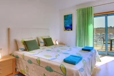 a bedroom with a large bed with blue pillows at Marina Sand Residence in Albufeira