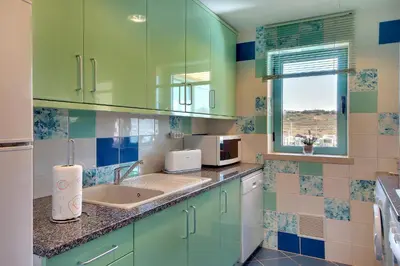 a kitchen with green cabinets and a sink at Marina Sand Residence in Albufeira