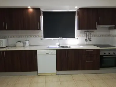 a kitchen with wooden cabinets and a sink and a window at Quinta Vita - Vila Maça in Loulé