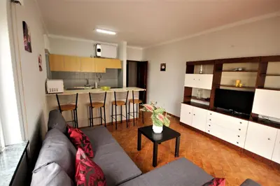 a living room with a couch and a kitchen at Apartamento Brás in Quarteira