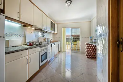 a kitchen with white cabinets and a tile floor at Apt O Monte C near the beach by Algarve Villa Holidays in Albufeira