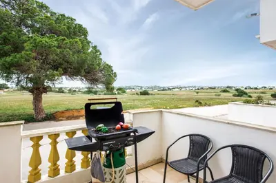 a grill on a balcony with chairs and a tree at Apt O Monte S by Algarve Villa Holidays in Galé