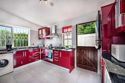 a kitchen with red cabinets and a washing machine at Buganvilia by Algarve Villa Holidays in Guia