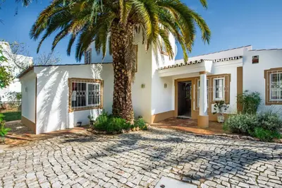 a palm tree in front of a white house at Buganvilia by Algarve Villa Holidays in Guia