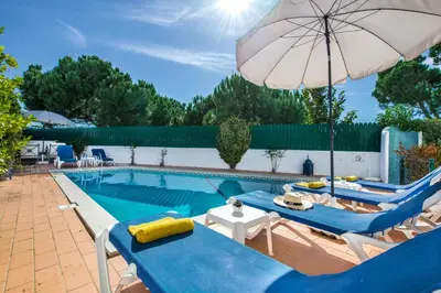 a pool with blue and white chairs and an umbrella at Julieta by Algarve Villa Holidays in Galé