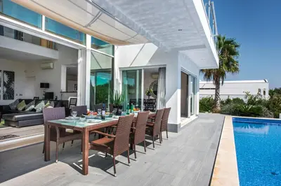 an outdoor dining room with a table and chairs next to a swimming pool at Vista Mar by Algarve Villa Holidays in Sesmarias