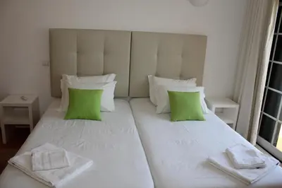 a large white bed with green pillows in a room at Villa V2 C in Albufeira