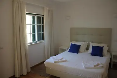 a bedroom with a bed with blue pillows and a window at Villa V2 C in Albufeira