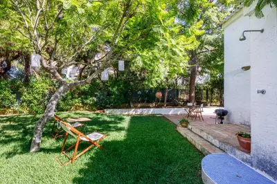 a yard with chairs and a tree in the grass at Pura Vida Falésia by The Portuguese Butler in Albufeira