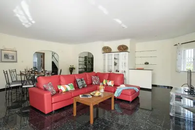 a living room with a red couch and a table at Vivenda Gabriel #vivgabriel in Albufeira