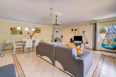 a living room with a couch and a dining room at Vila da Encosta - Private - Heated swimming pool - By bedzy in Albufeira