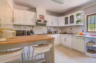 a kitchen with white cabinets and a counter with stools at Vila da Encosta - Private - Heated swimming pool - By bedzy in Albufeira