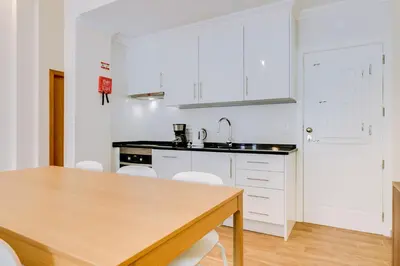a kitchen with a wooden table and white cabinets at Casa Azul Traditional House - Faro in Faro
