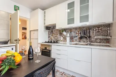 a kitchen with white cabinets and a table with fruit and wine glasses at Magic Theatre Faro Center in Faro