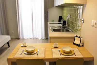 a kitchen with a wooden table with plates and bowls on it at Cardeal Suites & Apartments in Faro