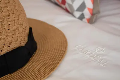a straw hat with a black strap sitting on a bed at Cardeal Suites & Apartments in Faro