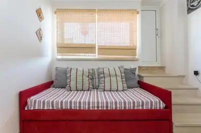 a red couch in a room with a window at Apartamento sobre a praia in Olhos de Água