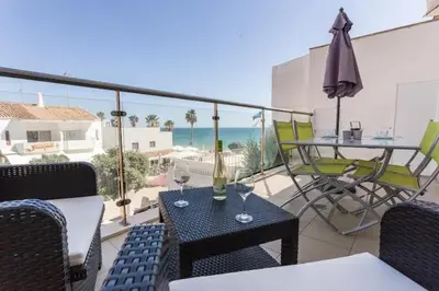 a balcony with a table and chairs and an umbrella at Apartamento sobre a praia in Olhos de Água